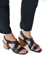 Sandalia de cuero negro con tira cruzada y taco medio, diseñada para comodidad y estilo.