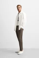 Pantalón slim fit negro confeccionado en tejido con elasticidad en ambas direcciones. Cuenta con bolsillos frontales y traseros de vivo con botón. Cierre frontal con cremallera y botón.