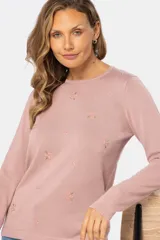 Buzo de tejido de punto color rosa, con bordado de flores pequeñas en el frente y mangas largas.