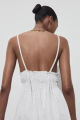 Vestido midi blanco de popelín con escote pico pronunciado, tirantes finos ajustables con cordones y detalle de frunces en la cintura.