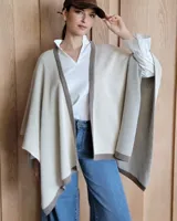 Ruana negra de tejido de punto con una estrella grande color beige en la espalda y borde inferior con franja beige.