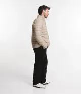 Campera puffer ultraligera color beige, con cuello alto, cierre por cremallera y bolsillos con cremallera. Incluye bolso de almacenamiento.