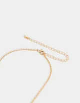 Collar corto dorado con cadena de eslabones y dijes colgantes: mariquita, trébol de cuatro hojas, herradura, corazón y cerezas.
