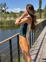 Top color beige de cuero con flecos en los laterales y caracoles buzios en el frente. Espalda tejida.