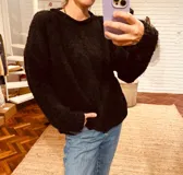 Sweater negro tejido en boucle, de corte holgado y cuello redondo.