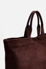 Bolso tipo shopper marrón de piel con acabado serraje. Tiene dos asas de mano y un bolsillo interior con cierre.