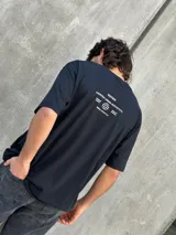 Remera negra de corte oversize con estampado en la espalda con la leyenda "OSTEN EVERYDAY URBAN AESTHETICS PREMIUM BASICS QUALITY APPAREL URBAN LIFESTYLE".