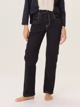 Pantalón de jean recto color negro, confeccionado en gabardina gastada, con pespuntes y atraques en hilo de color claro contrastante.