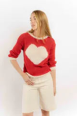 Sweater rojo tejido a mano con hilo, de corte holgado y cuello redondo. Presenta detalles en color crudo en el cuello, puños y ruedo.