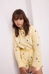 Camisa negra con bordado de flores rosas, corte recto, cuello clásico y cierre frontal con botones.