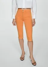 Pantalón capri color naranja, de tiro medio, corte skinny y cierre frontal con cremallera. Confeccionado en tejido de algodón estilo tejano vaquero.