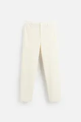 Pantalón color crudo de tejido con textura de rizo, corte relaxed fit, con cintura elástica, bolsillos frontales y traseros, cierre frontal con cremallera y botón.