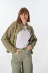 Cardigan color crudo de tejido de punto con diseño trenzado, cuello alto y cierre frontal con cremallera.