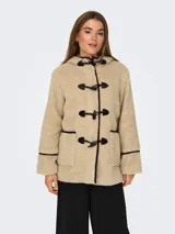 Abrigo de tela tipo teddy color beige, con capucha, cierre con botones tipo duffle coat y bolsillos frontales. Detalles en cuero sintético negro en los bordes y en los botones.