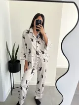 Conjunto de pijama blanco con estampado de tigres negros, ribetes negros, camisa de manga larga con botones y pantalón largo.
