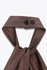 Chaleco top marrón con cuello halter, detalle de nudo y cierre frontal con botones.