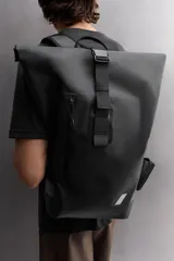 Mochila negra de tejido técnico con compartimento principal con cierre de hebilla de liberación rápida, bolsillo termosellado frontal con cremallera, asa de mano y dos asas de hombro ajustables.