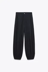 Pantalón bombacho de denim azul oscuro, tiro medio, con bolsillos laterales ocultos y de parche en la espalda. Presenta pinzas en la parte delantera y bajo abullonado con elástico.