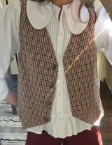 Chaleco marrón con estampado de pata de gallo, con botones al frente y corte recto.