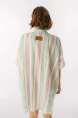 Camisa oversize con cuello mao, manga corta con terminación en puño, botones de metal a la vista y tajos laterales.