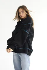 Buzo negro de felpa de algodón con pespuntes en zigzag color celeste y logo bordado en el pecho.