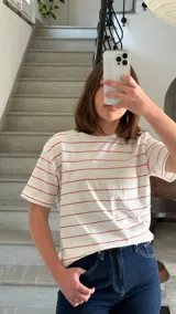 Camiseta blanca con rayas horizontales rojas y logo bordado en el pecho.