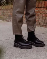 Botas cortas color beige con cierre frontal de cremallera, suela track negra y tirador trasero.