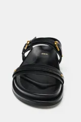 Sandalias planas negras con tiras y hebillas.