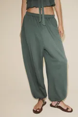 Pantalón bombacho color marrón de felpa de algodón, con cintura elástica, tiro alto, bolsillos laterales y puños elásticos en los tobillos.