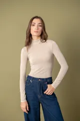 Polera de mujer de tejido suave y ajustado color beige, con cuello alto y manga larga.