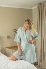 Bata tipo kimono celeste con estampado de líneas blancas, mangas 3/4 y lazo de ajuste en la cintura.