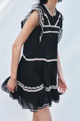 Minivestido negro de algodón con bordados florales blancos en cuello, mangas y ruedo.