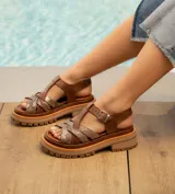 Sandalias bajas de cuero vacuno color beige con tiras cruzadas plateadas y hebilla lateral. Suela doble de goma deportiva con altura de 3cm adelante y 5,5cm atrás.