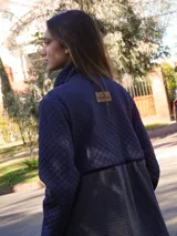 Campera con cierre frontal, de corte entallado, con parte superior acolchada en color negro y parte inferior en tweed gris.