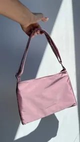Cartera de lona semi impermeable en color rosa, con cierre metálico y bolsillo interno.