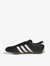 Zapatillas Adidas Tokyo negras con detalles en blanco y suela marrón.
