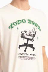 Remera unisex color crema de algodón, con cuello redondo y estampado frontal con la frase "TODO BIEN" en verde y un dibujo de una silla de oficina.