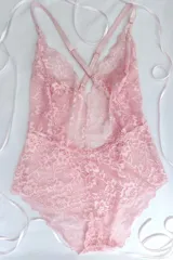 Body de encaje elastizado color rosado, con espalda baja y breteles elásticos regulables cruzados en la espalda.