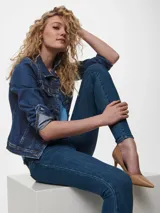 Chaqueta de jean azul oscuro con cuello clásico, cierre frontal con botones metálicos y mangas largas con puños abotonados.