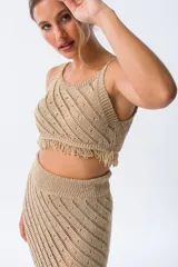 Musculosa tejida color dorado con diseño calado y flecos en el ruedo.