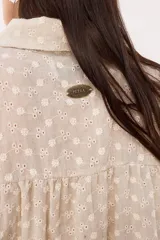 Camisa celeste a rayas verticales blancas, con cuello clásico, cierre frontal con botones y mangas largas abullonadas con puños elásticos.