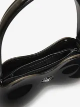Bolso de hombro con forma orgánica tridimensional, inspirado en un control de videojuegos. Construcción rígida soft-touch, color negro brillante con detalles en marrón oscuro en los bordes. Posee un remache metálico ovalado en el frente y correa fija al hombro.