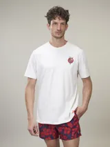 Remera de manga corta color crudo con cuello redondo y pequeño estampado de corazón con flores en el pecho.