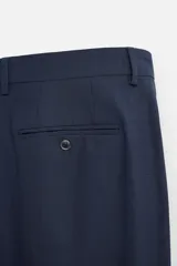 Pantalón de vestir azul marino, de corte slim fit, con bolsillos laterales y traseros de doble vivo con botón. Se ajusta a la cintura con cierre frontal con cremallera y botón.