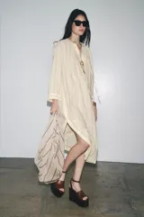 Vestido tipo túnica color crudo con rayas verticales negras, cuello redondo con escote pico ajustable con lazadas y mangas largas.