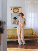 Pantalón sastrero color crema de tiro medio con pierna ancha y pliegue marcado.