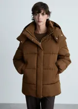 Campera puffer marrón con capucha, cierre frontal con cremallera y botones a presión, bolsillos laterales y puños elásticos.