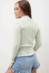 Polerita de punto color verde claro, con cuello alto y diseño ajustado.