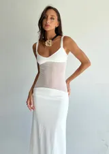 Vestido largo blanco con breteles finos y paneles de tela traslúcida en la zona del torso y la cadera.