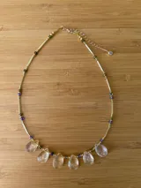 Collar dorado con cuentas de colores y colgantes de cristal transparente en forma de lágrima.